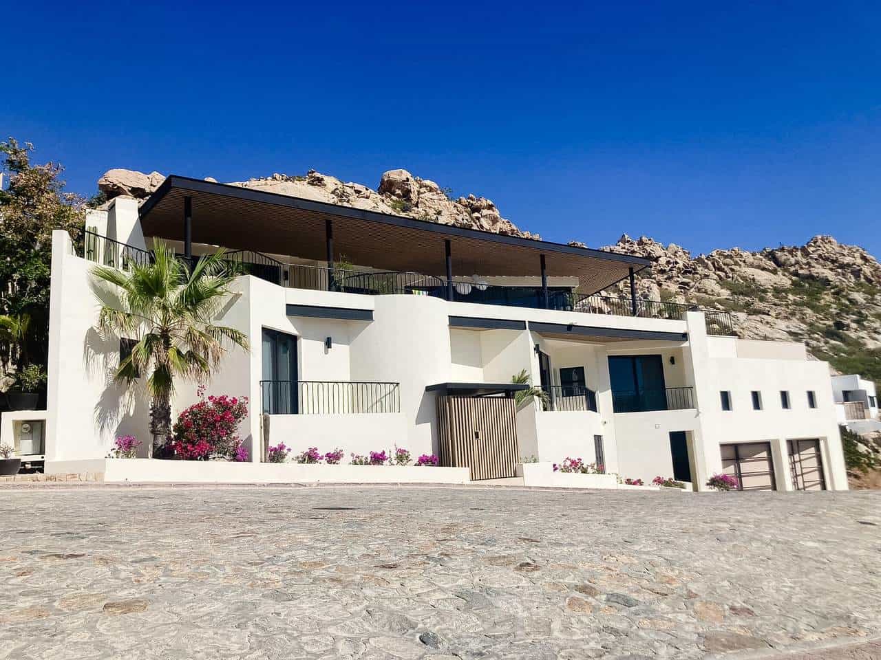 Stunning Pedregal Modern Villa With White Exterior, Spacious Terraces, And Mountain Backdrop Under Clear Blue Sky.