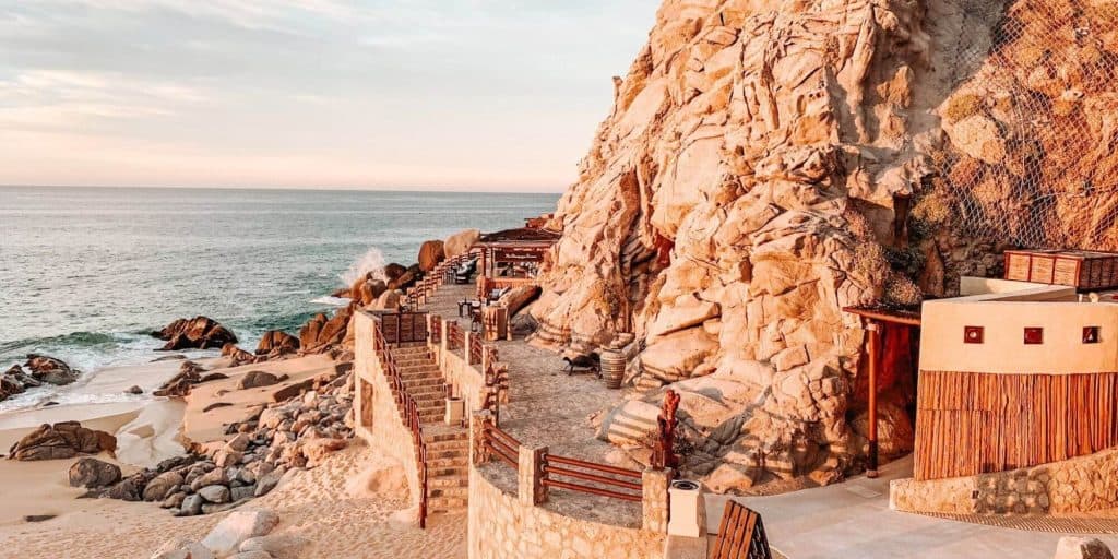Living In Pedregal Cabo β What Makes This Cliffside Community So Special β Homes For Sale In Pedregal Stunning Pedregal Oceanfront View Showcasing A Private Terrace With Stairs, Rocky Cliffs, And The Expansive Sea In The Background, Capturing The Luxurious Coastal Lifestyle.