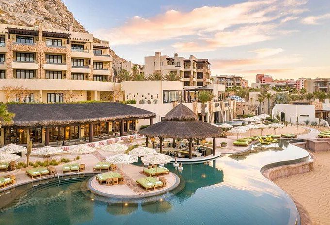 Winding Infinity Pool With Swim-Up Bar And Thatched Roof Palapa At A Luxury Resort In Pedregal, Cabo San Lucas.